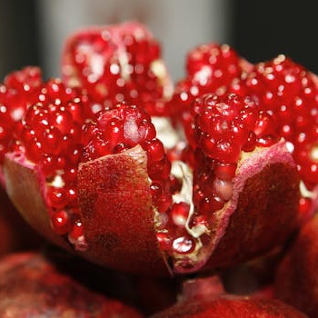 Detailed macro shot of a fresh, vibrant pomegranate exposing its juicy seeds.